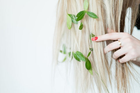 Nahaufnahme von blondem Haar mit grünen Blättern für natürliche Haarpflege