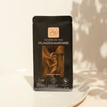 That's Me Organic Pflanzenhaarfarbe Warm Nougat Brown auf weißem Teller, beige Hintergrund
