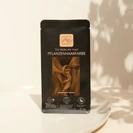 That's Me Organic Pflanzenhaarfarbe Warm Nougat Brown auf weißem Teller, beige Hintergrund