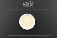 Weiße Schale mit Bio Ziegen Ghee auf schwarzer Unterlage mit Vitanu Logo und Maßstab