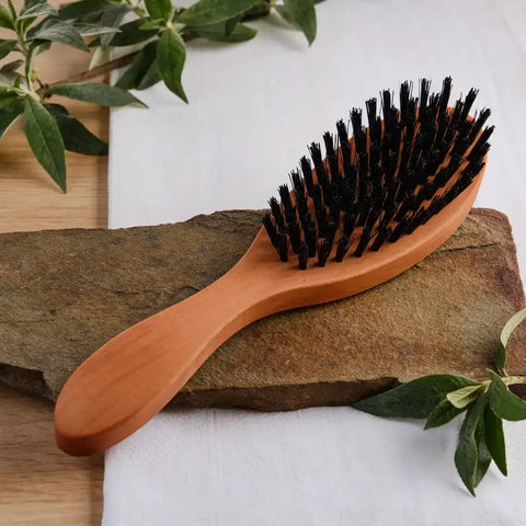 Holzbürste mit schwarzen Naturborsten auf Steinplatte, natürliche Dekoration, Produktfoto