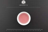 Weiße Schale mit rosa Gold-Kolloid-Lösung auf schwarzer Unterlage, Maßstab und Logo