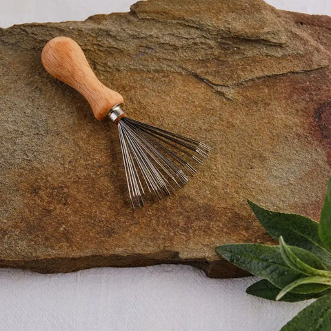 Mini-Gartenrechen mit Holzgriff auf Naturstein, Gartengerät, Kräuterpflanze am Rand