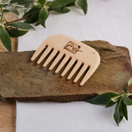 Holzkamm für Locken, grobe Zinken, auf Stein mit grünen Blättern, Naturkosmetik