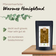 Pflanzenhaarfarbe warmes Honigblond Packung auf Holztisch mit Produktbeschreibung und Blättern.