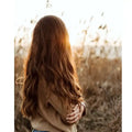 Frau mit langen braunen Haaren im Sonnenlicht auf einem Feld, Natur, Herbststimmung