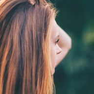 Frau mit langen, glatten, braunen Haaren im Grünen, Natur, Seitenansicht, entspannte Atmosphäre