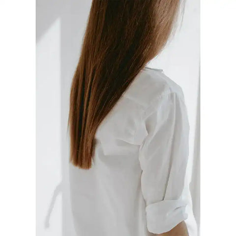 Langes, glattes braunes Haar, weiße Bluse, helles natürliches Licht
