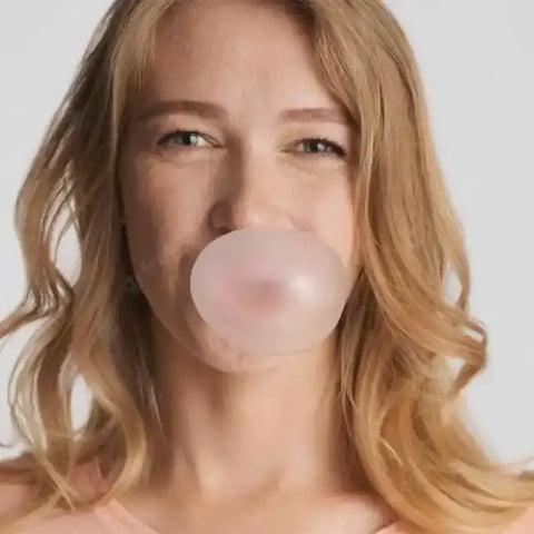 Frau mit blonden Haaren macht eine Kaugummiblase, Nahaufnahme, neutraler Hintergrund