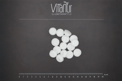 Weiße Xylit Zahnkristalle für Kinder auf schwarzem Hintergrund mit Lineal, VitaNur Logo