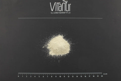 Beiger Zahnpulver-Hügel auf schwarzem Hintergrund mit VITANUR-Logo und Zentimeterskala