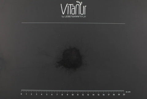 Schwarzes Zahnpulver von Vitanur auf schwarzem Hintergrund mit Messskala, Zahnpflege Produkt